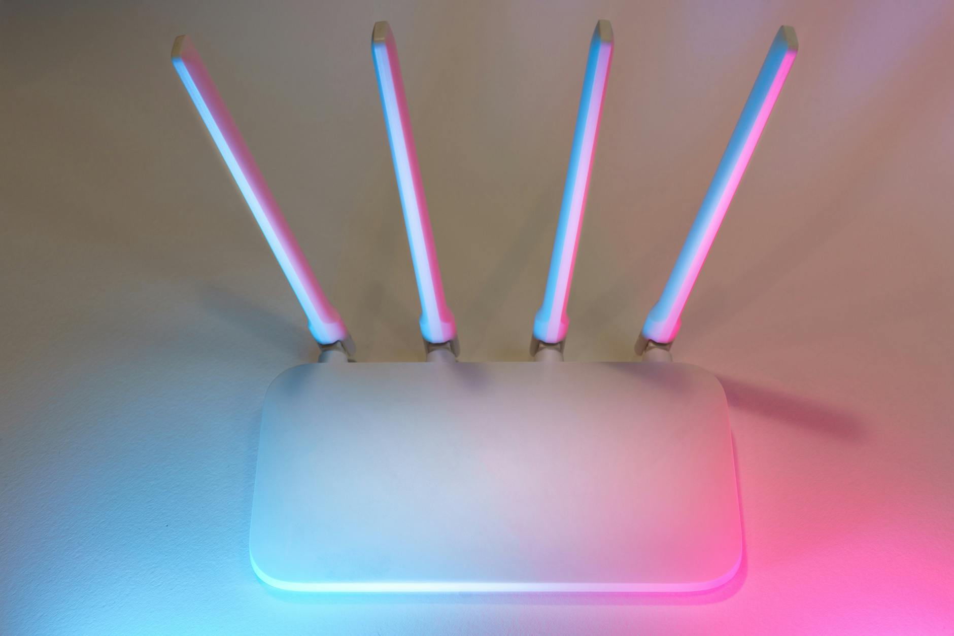 Nowoczesny biały router Wi‑Fi z czterema antenami na kolorowym tle światła