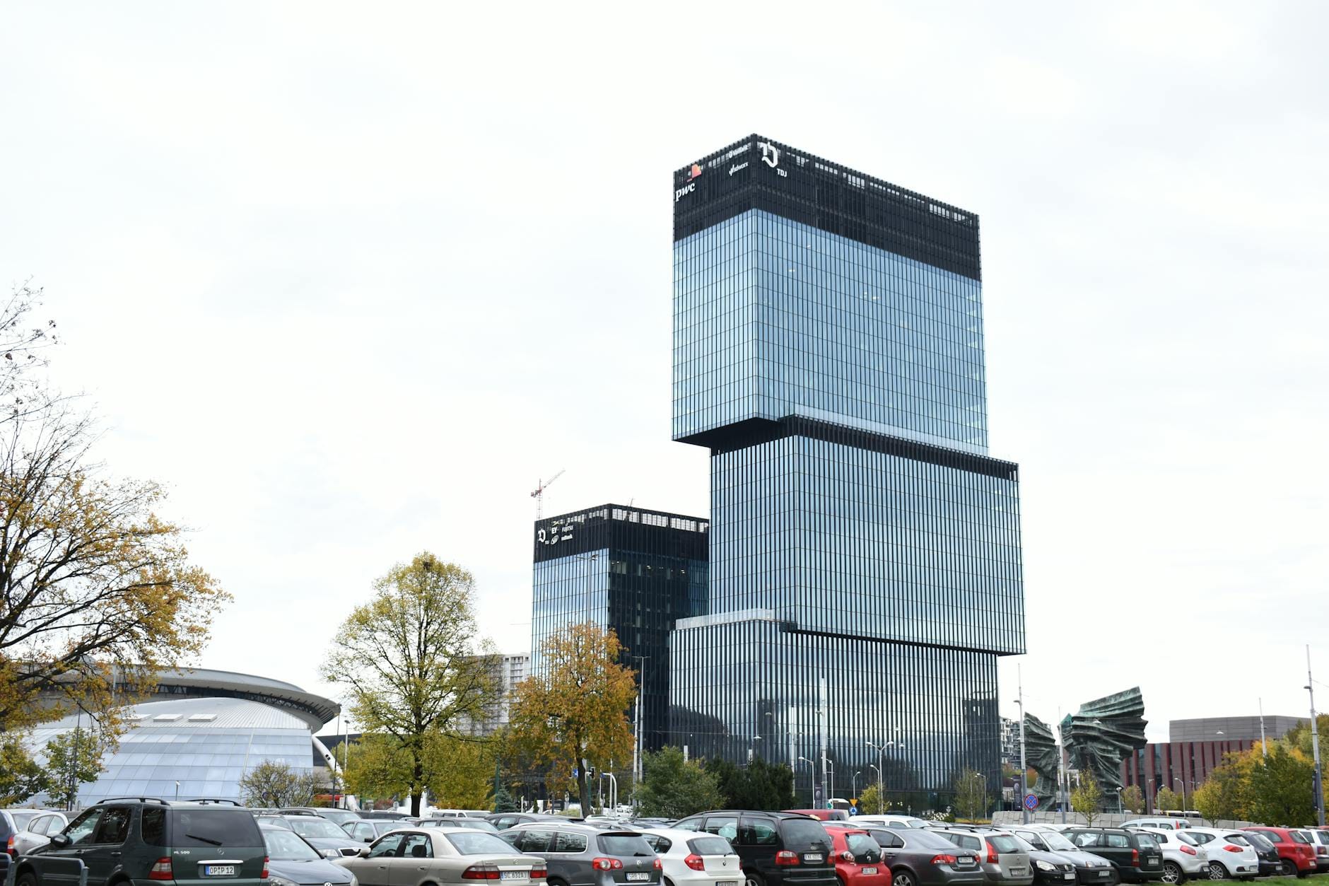 Nowoczesny biurowiec w centrum Katowic z samochodami i drzewami przed budynkiem