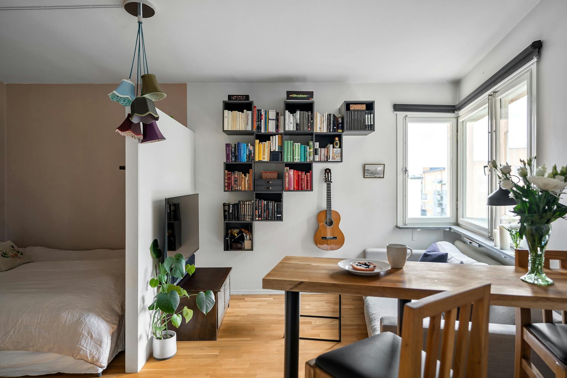 Jasna mikrokawalerka w Katowicach z regałem, gitarą i małym stołem