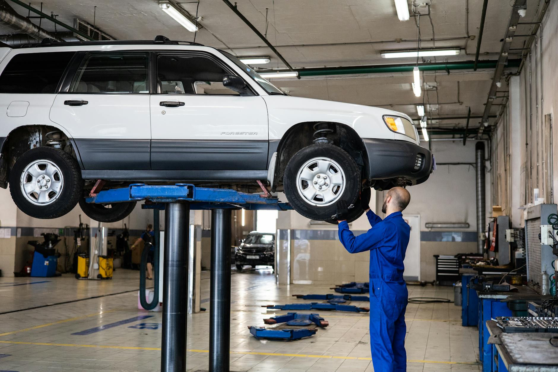 Mechanik ogląda białe SUV w jasno oświetlonym warsztacie samochodowym
