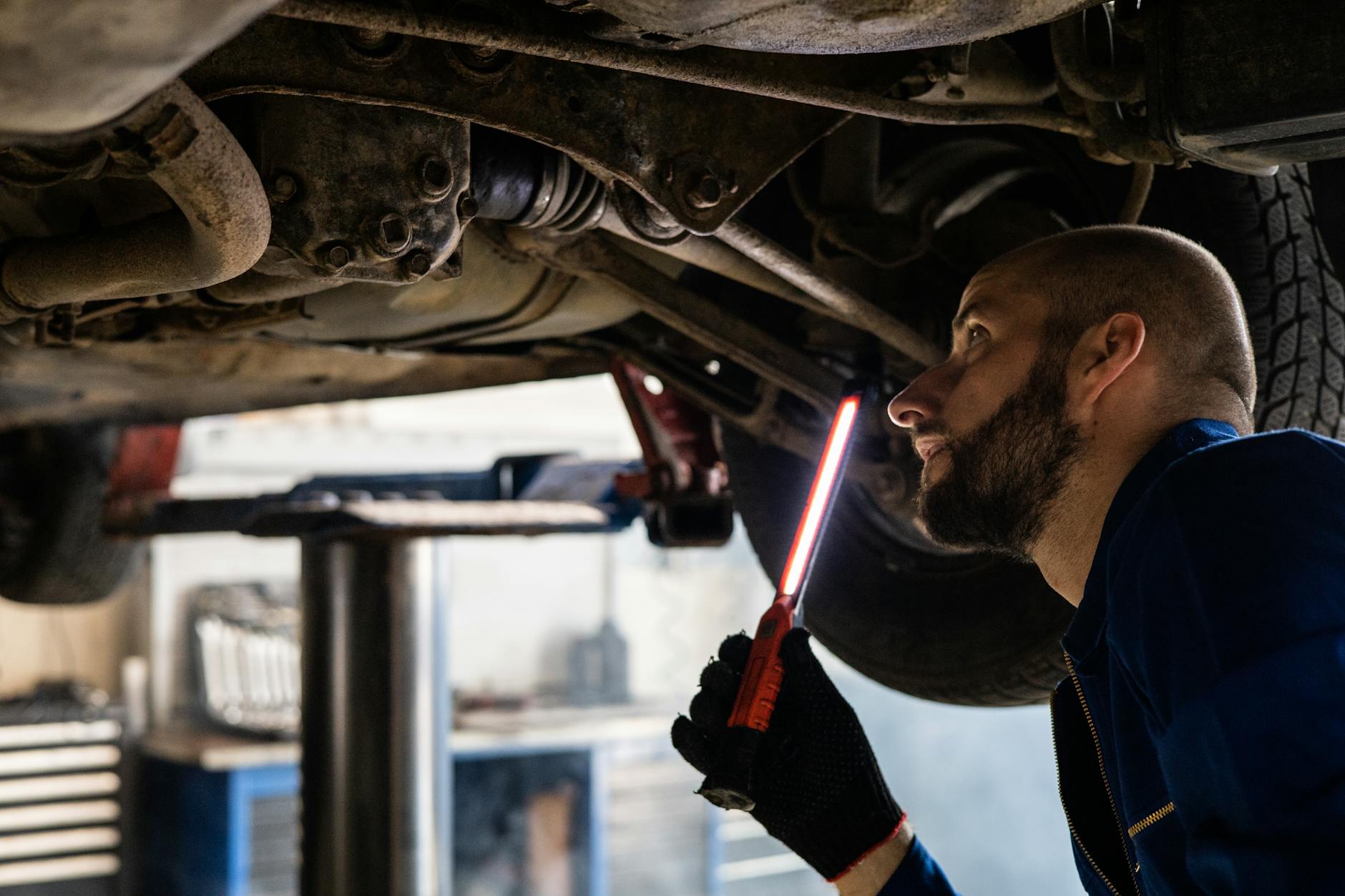 Mechanik z latarką sprawdza podwozie samochodu w warsztacie