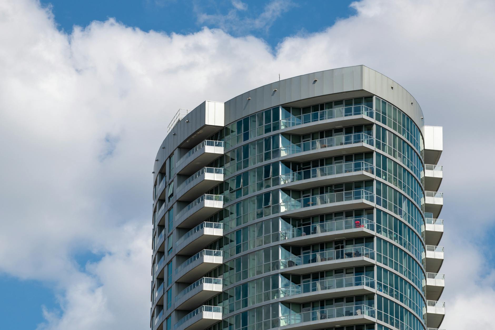 Nowoczesny wieżowiec mieszkalny na tle błękitnego nieba z chmurami